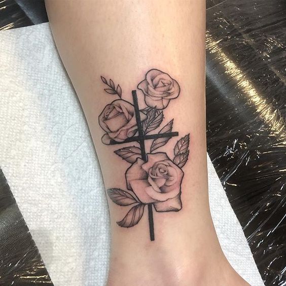 a cross and roses tattoo on the foot