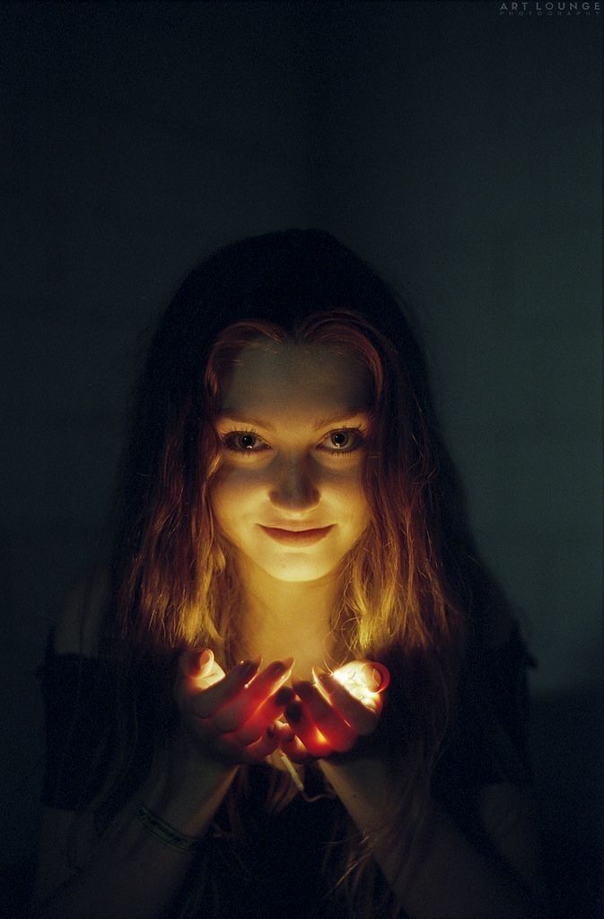 a woman holding her hands in front of her face with the light shining on her