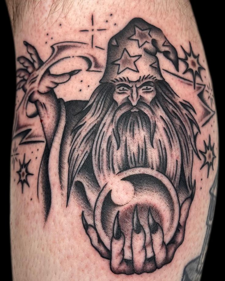 a man with a wizard hat and beard tattoo on his arm is holding an object