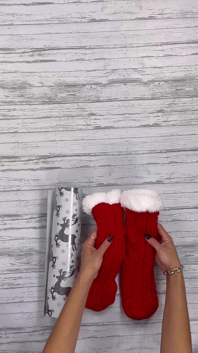 someone is holding up their red slippers in front of a present box and wrapping paper