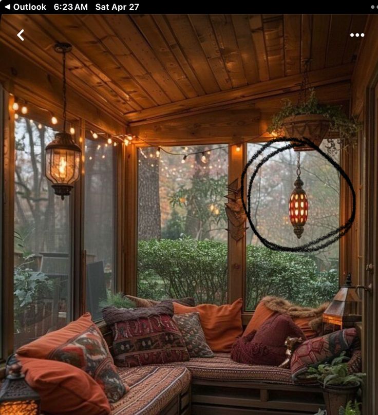 a screened porch with lots of pillows and lights