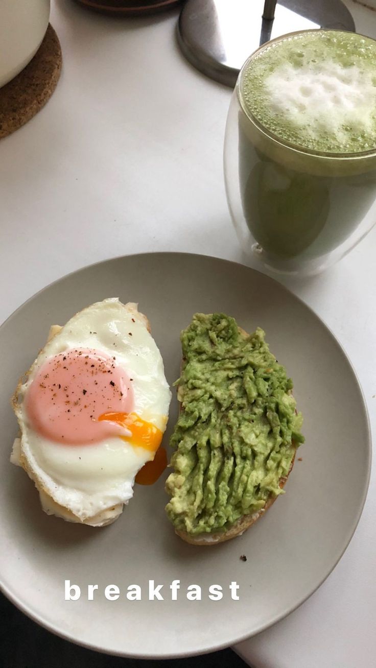 an egg and guacamole sandwich is on a plate next to a drink