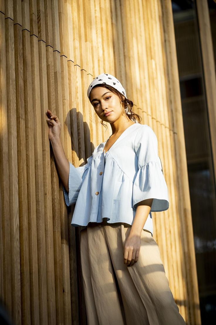 a woman leaning against a wooden wall