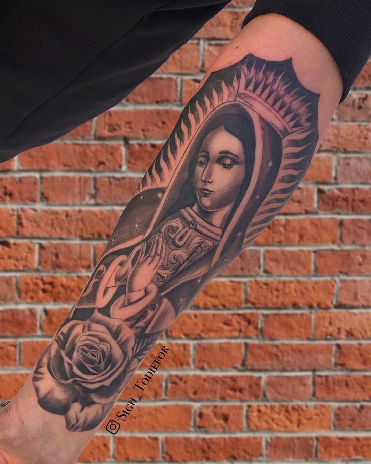 a person with a tattoo on their arm holding a rose and an image of the virgin mary