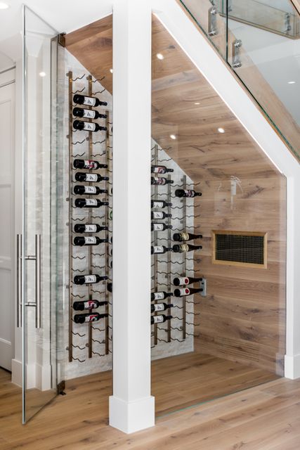 a wine cellar in the corner of a room with wooden flooring and glass walls