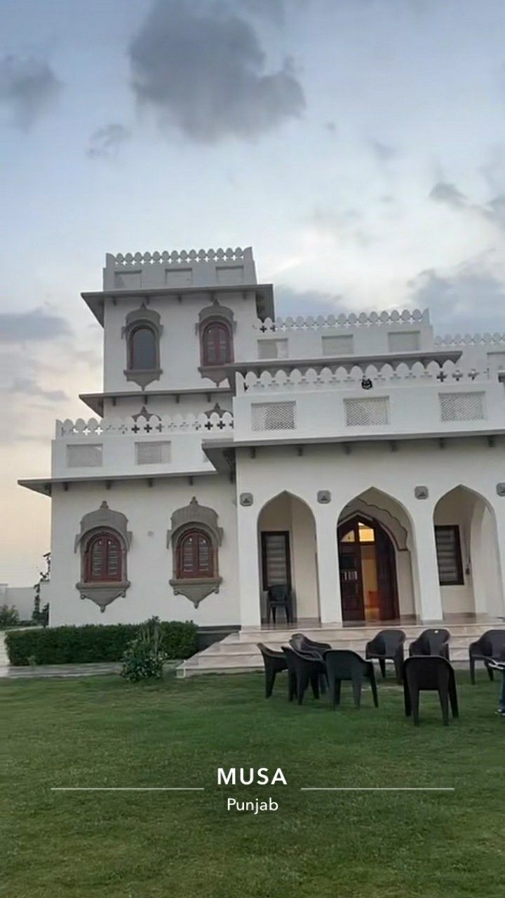 a large white house sitting on top of a lush green field under a cloudy sky