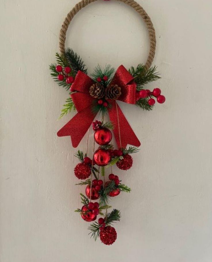 a christmas wreath hanging on the wall with pine cones and red berries attached to it