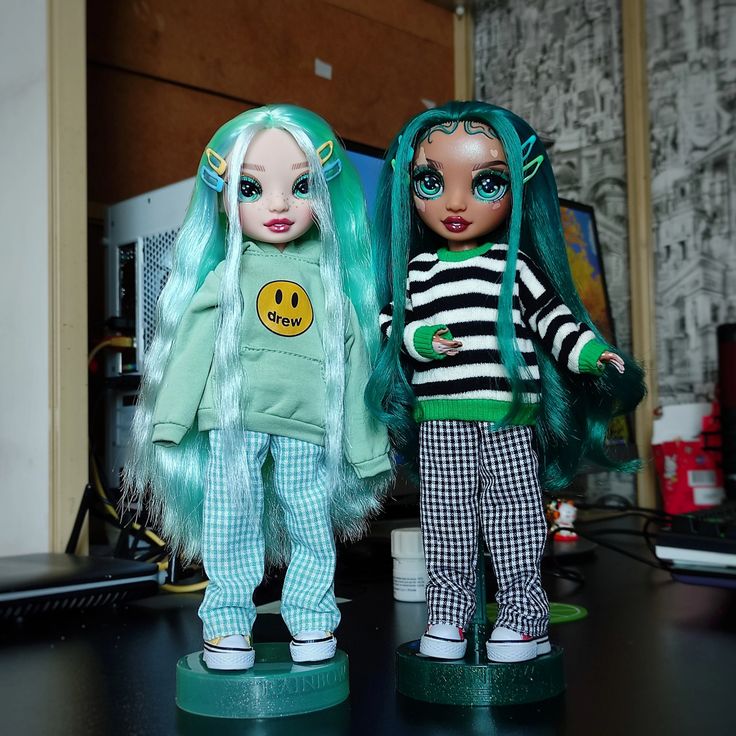 two dolls standing next to each other on a table