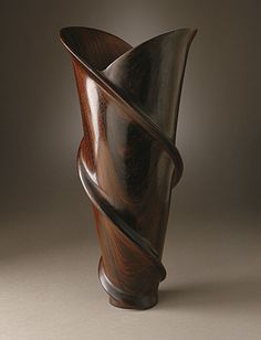 a wooden vase is shown with a twisted design on the top and bottom side,