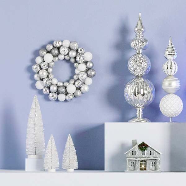 christmas decorations are displayed on a shelf in front of a blue wall with a wreath