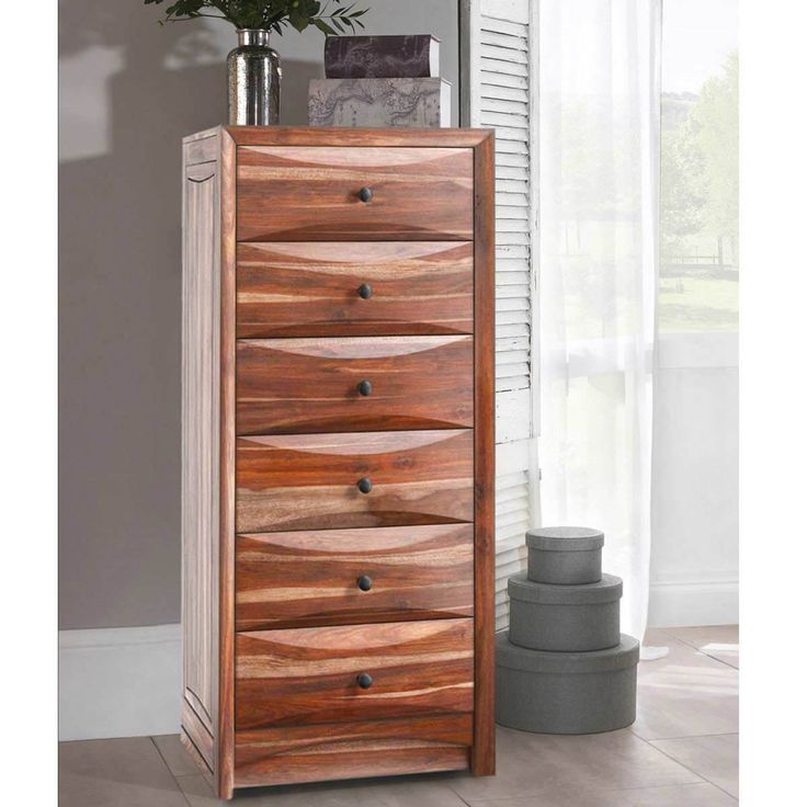 a wooden chest of drawers sitting next to a vase with flowers on top of it