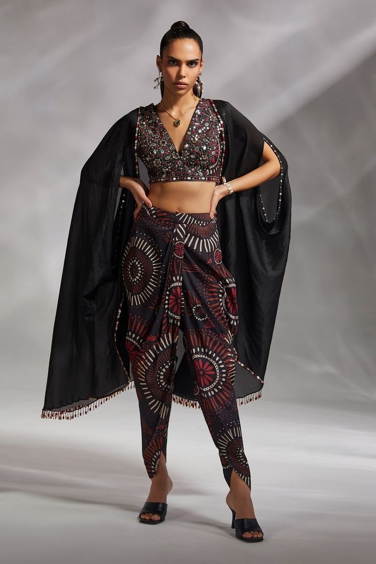 Black crushed organza oversized cape with embroidery and tassel details. Comes with padded blouse and printed dhoti pant.
Component: 3
Pattern: Print and Embroidery
Type Of Work: Geometric Print and Bead, Tassel Embroidery
Neckline: Blouse: V Neck, Cape: Open
Sleeve Type: Blouse: Sleeveless, Cape: Split
Fabric: Cape: Crushed Organza, Blouse and Dhoti Pant: Silk Dupion
Color: Black
Other Details: 
Attached lining
Approx weight (in kg) : 800 gms
Note: The neckpiece worn by the model is not for sal Divya Aggarwal, Cape Pants, Tassel Embroidery, Blouse Yoke, Print And Embroidery, Dhoti Pants, Black Cape, Embellished Blouse, Indian Couture