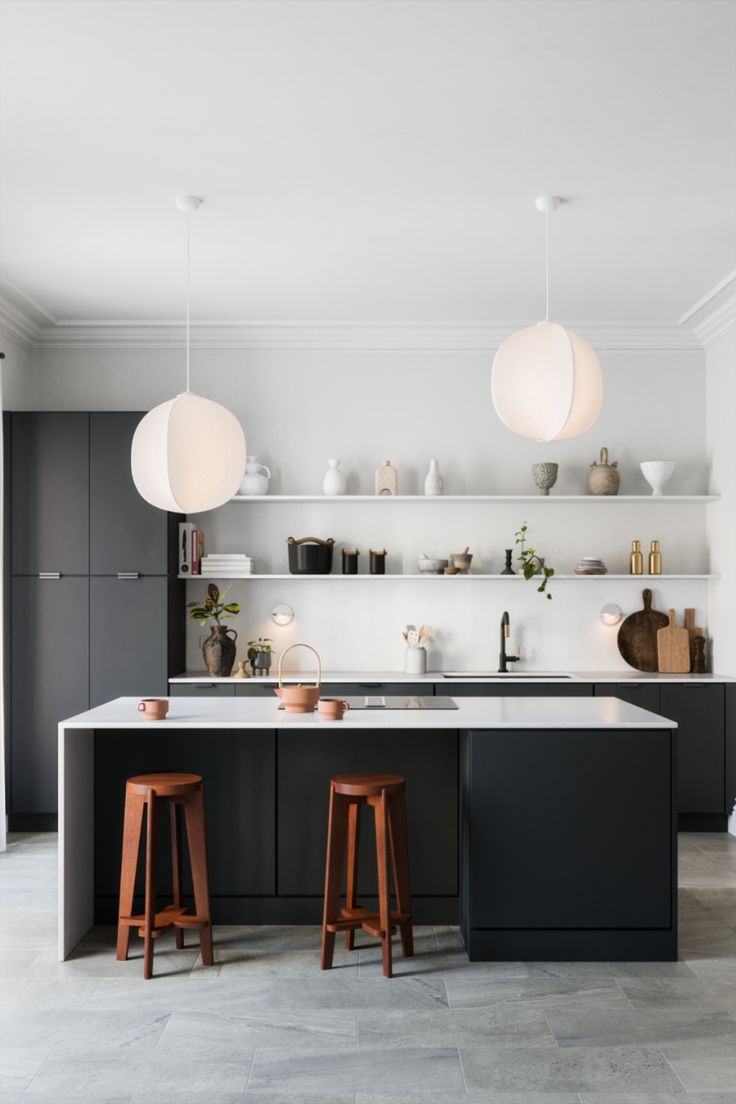 an open kitchen with two stools in front of the counter and shelves on the wall