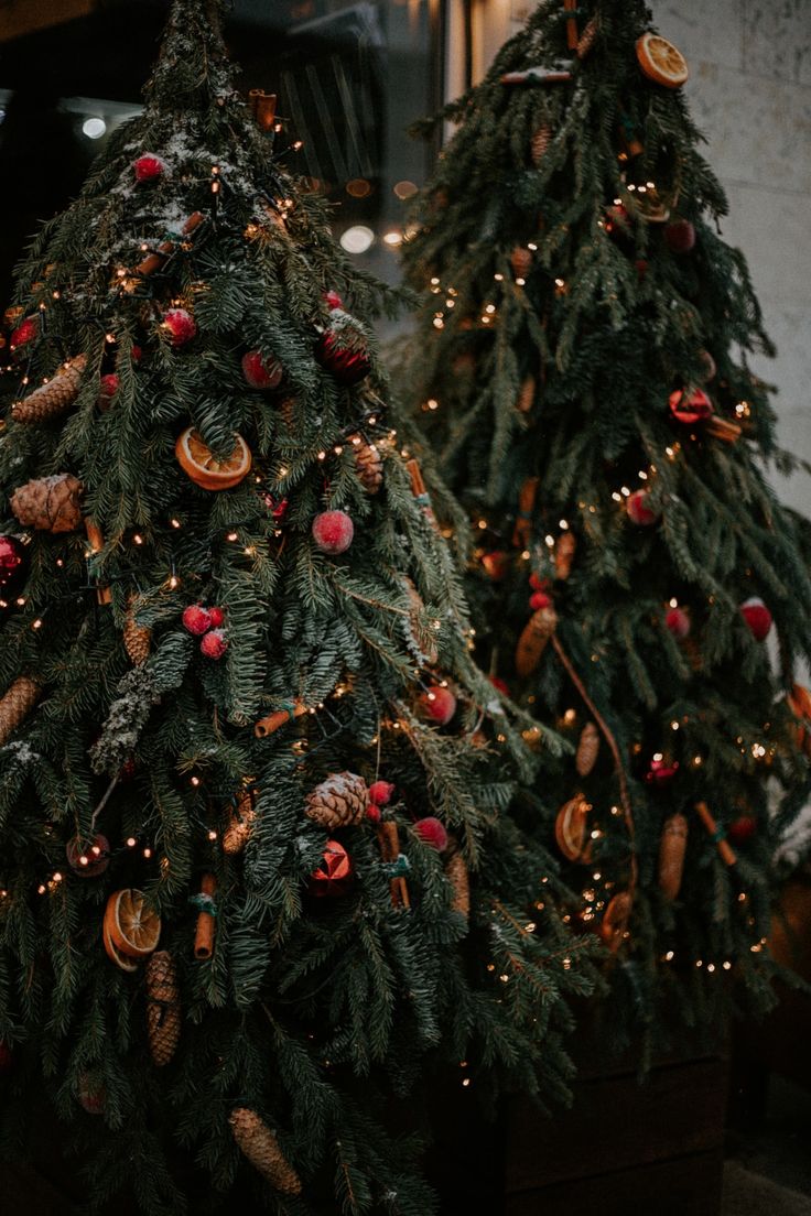 two christmas trees decorated with ornaments and lights