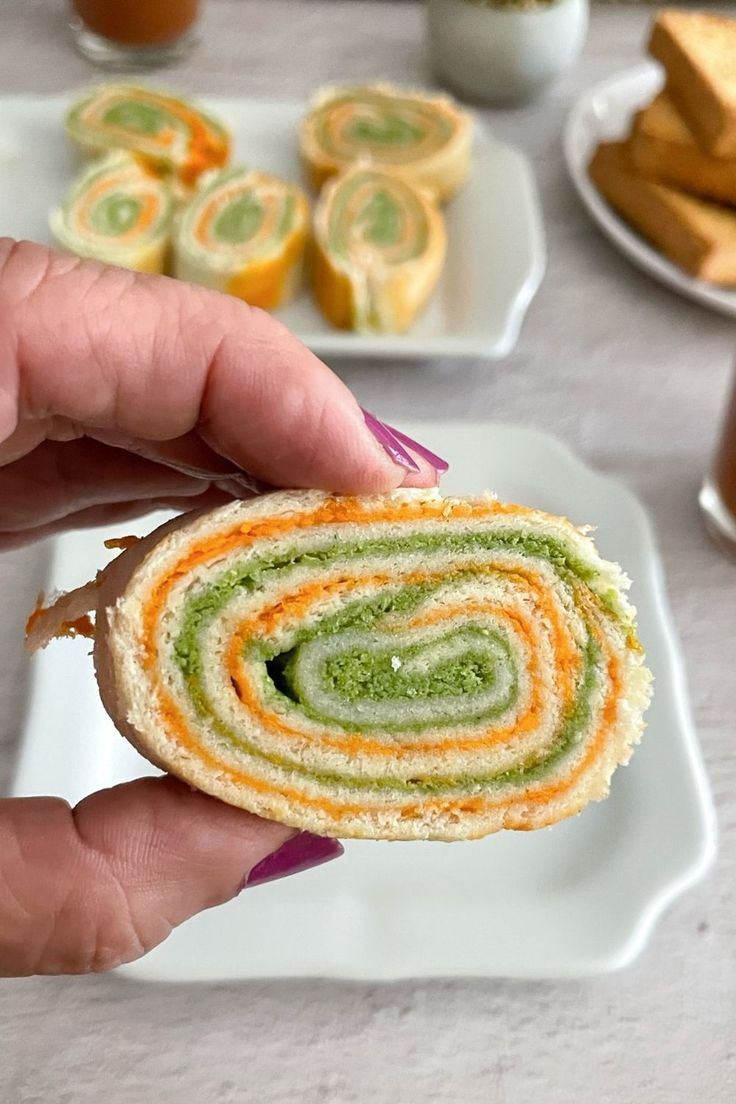 a person is holding up a sandwich that has been rolled in half on a plate