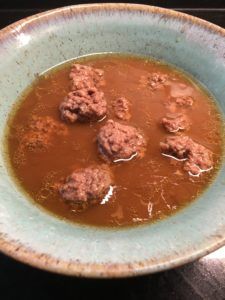 a bowl filled with meatballs and gravy on top of a wooden table