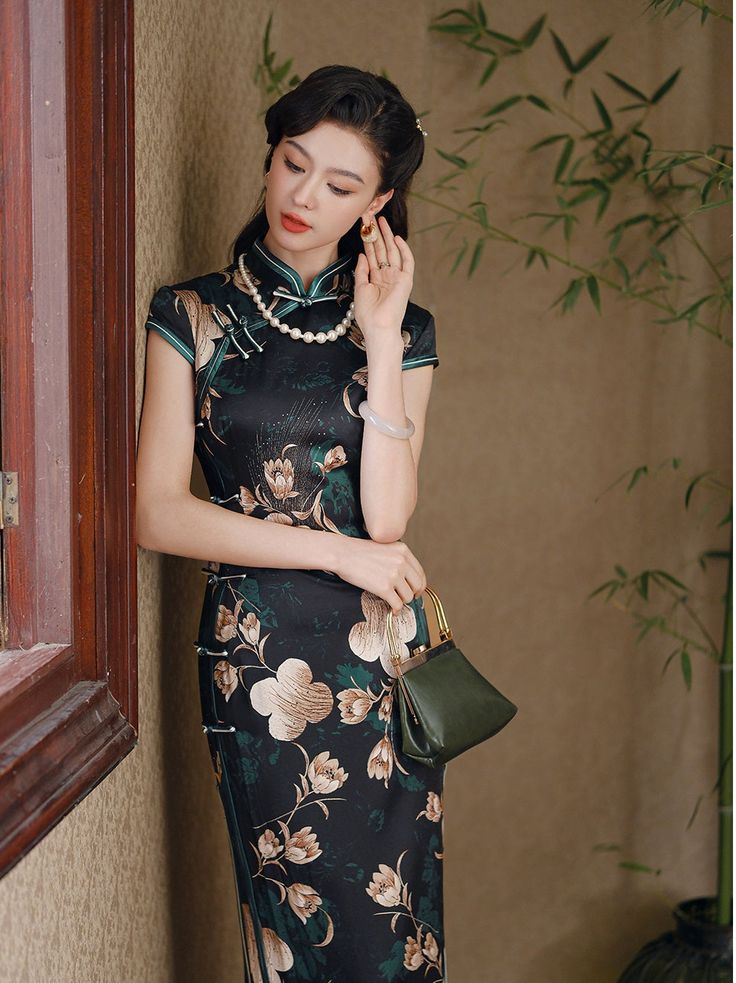 Step into elegance with this luxurious black silk qipao adorned with an exquisite floral design. The dress features a high Mandarin collar and traditional frog buttons, giving it a refined, authentic look. The rich green floral motif, interspersed with delicate cream and gold blossoms, adds a touch of nature-inspired beauty, making it perfect for formal occasions, evening events, or as a statement piece for special gatherings. Material: 90% Mulberry Silk, 10% Spandex Size Guide: Please note Asia Elegant Floral Print Cheongsam With Stand Collar, Green Elegant Cheongsam With Stand Collar, Elegant Green Cheongsam With Stand Collar, Elegant Fitted Cheongsam With Floral Print, Traditional Floral Print Formal Dress, Elegant Black Cheongsam For Spring, Elegant Green Dress With Stand Collar, Traditional Black Dress With Floral Print, Traditional Black Floral Print Dress