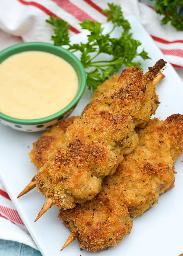 chicken skewers on a plate with dipping sauce