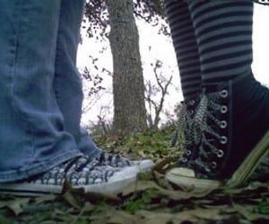 two people standing next to each other with their feet on the ground and one person's legs crossed