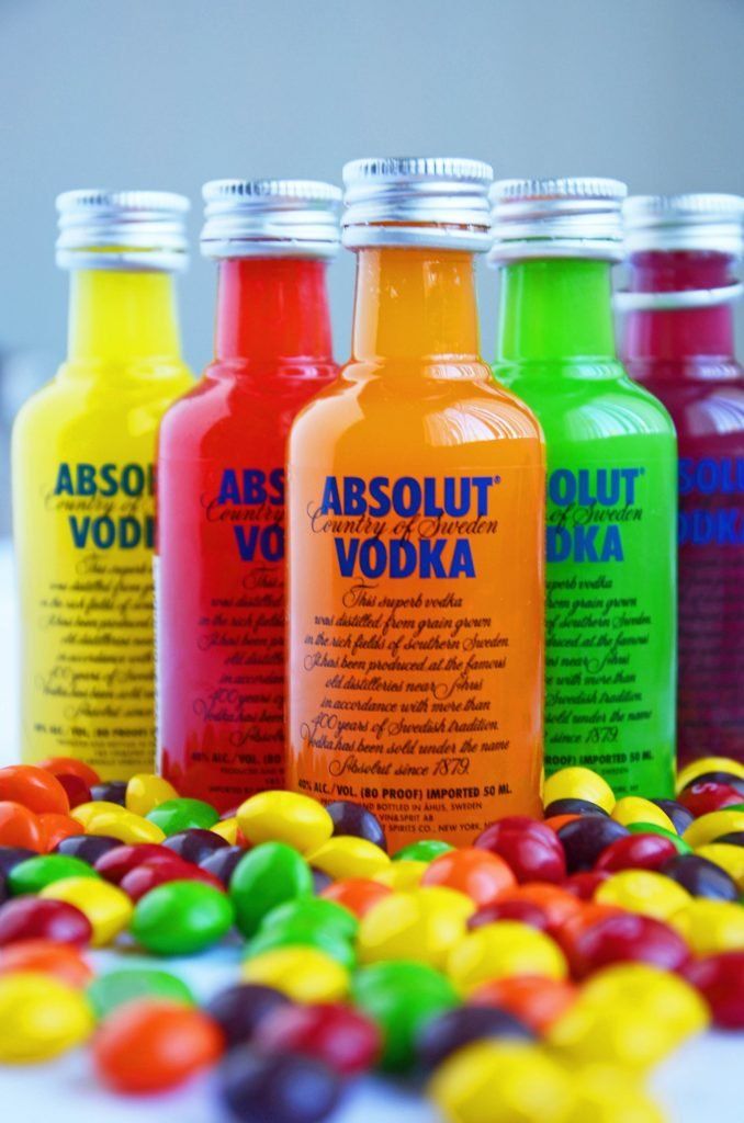 four bottles of vodka sitting next to each other on top of candy candies in front of them