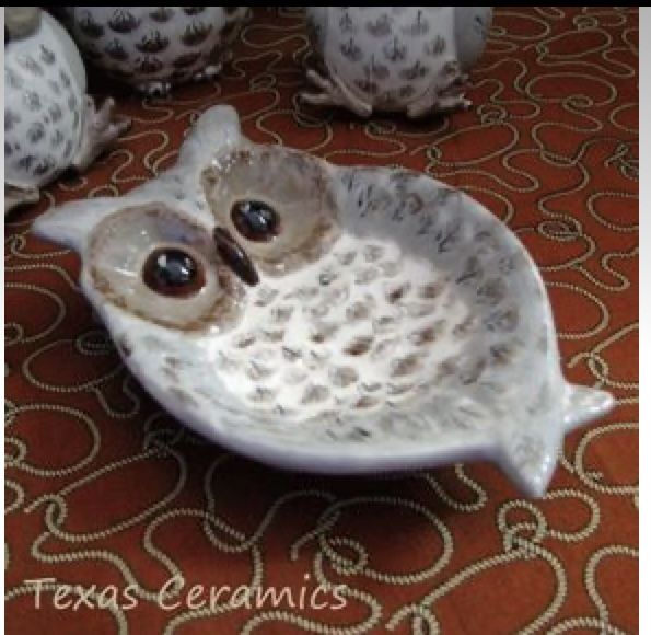 an owl figurine sitting on top of a white bowl next to other owls