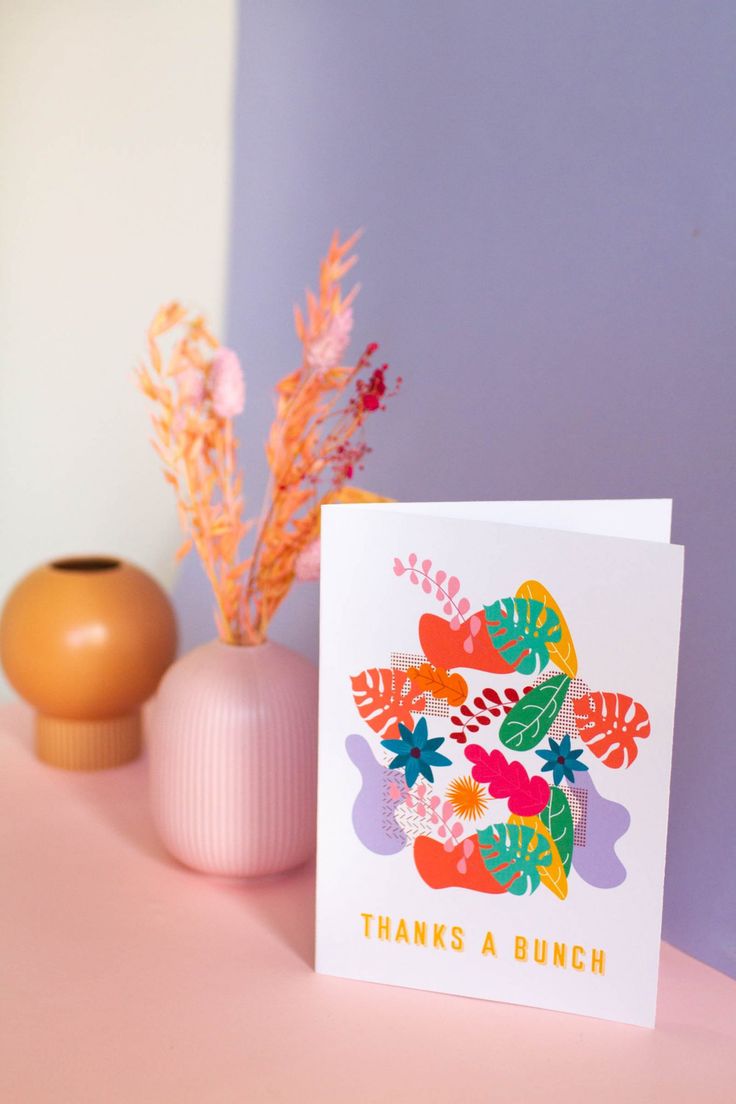 there is a card that says thanks a bunch on it next to a vase with flowers