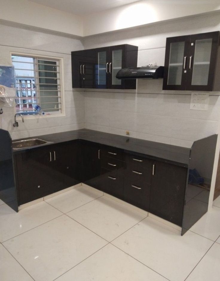 an empty kitchen with black cabinets and white tile flooring