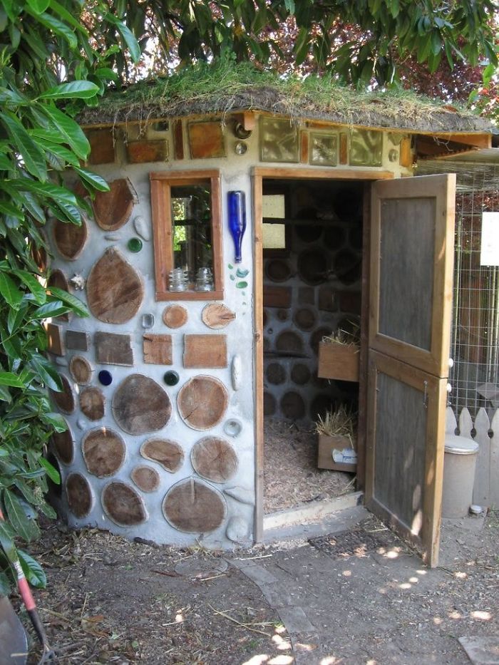 an outhouse made from rocks and wood with a grass roof on the top floor