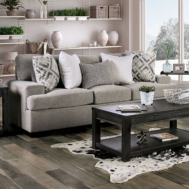 a living room filled with lots of furniture next to a large window covered in potted plants