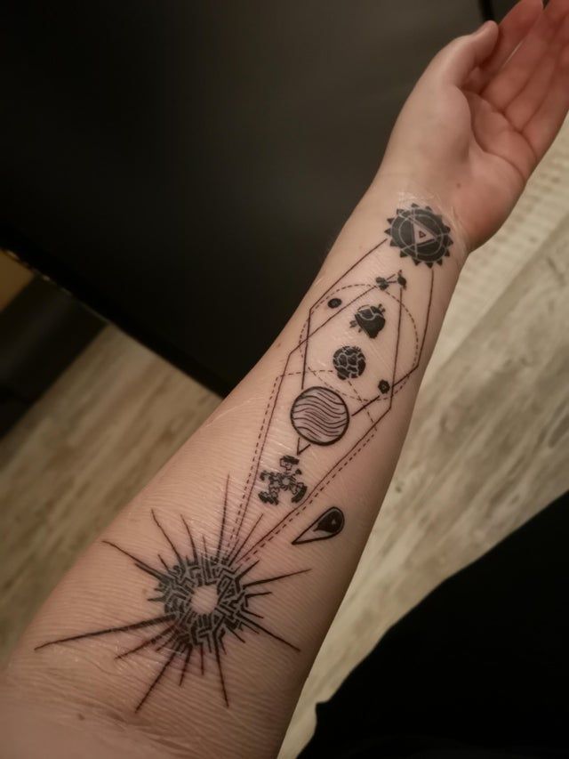 a person's arm with tattoos on it and planets in the sky above them