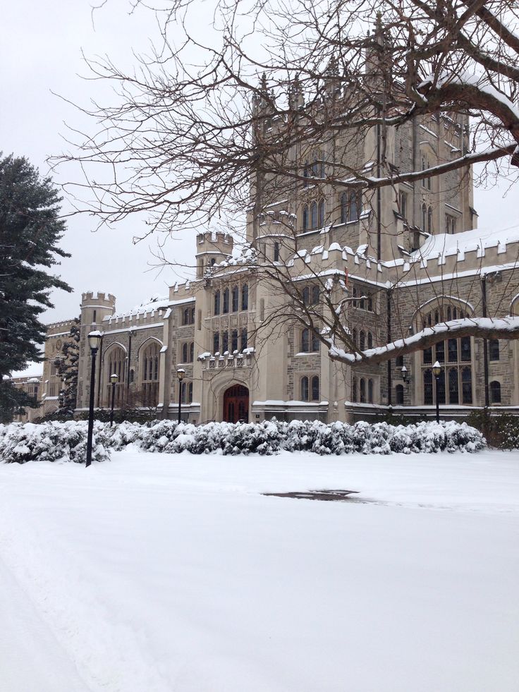 a large building that has snow on the ground in front of it and some trees