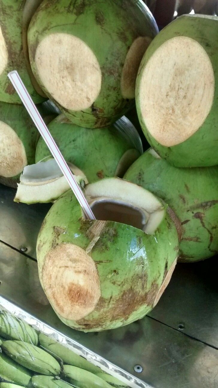 a pile of green coconuts sitting on top of a metal tray next to bananas