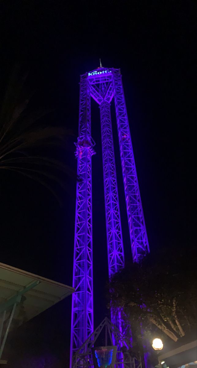 the tall tower is lit up with purple lights