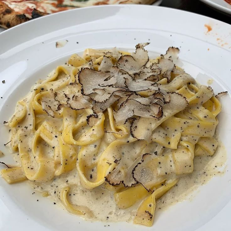 a white plate topped with pasta covered in sauce and mushrooms on top of pizzas