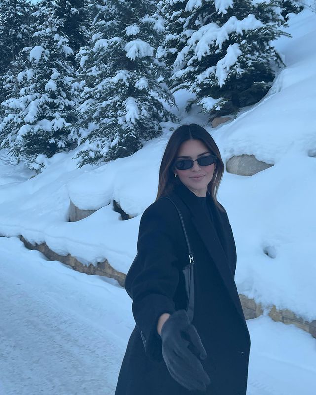 a woman standing in the snow wearing sunglasses