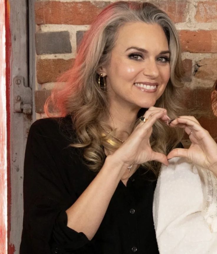 two women standing next to each other in front of a brick wall