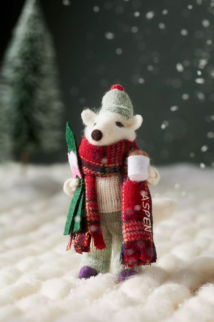 a small teddy bear wearing a red and green scarf holding a bottle in it's hand