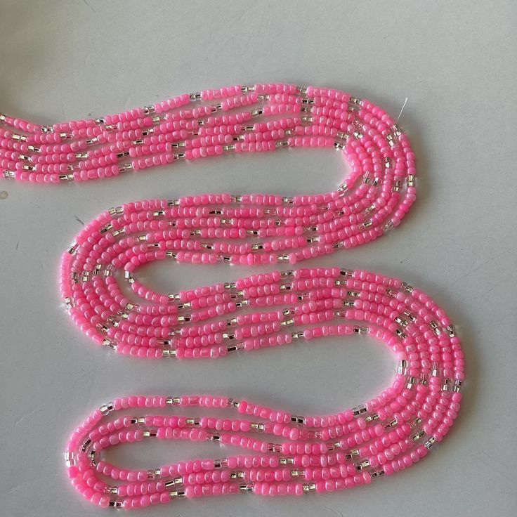 This uniquely and beautifully handcrafted. Women waist beads. Made with mixture of seeds and glass beads. Each strand is measured approximately 60 inches long.  Each purchase is 1 strand of waist bead of your choice  helps gets your waist snatched and beautifies your waist  Ready to ship. This is Tie on waist beads. Color of beads: Pink and silver. Size of beads 3mm. Materials used: beads/ friendly thread Multi-strand Beaded Waist Beads For Festival, Bohemian Heishi Beaded Waist Beads, Bohemian Beaded Chain Waist Beads, Colorful Heishi Waist Beads, Pink Spacer Beads For Festival, Pink Waist Beads With 108 Beads As A Gift, Adjustable Pink Waist Beads With Spacer Beads, Colorful Waist Beads For Festivals, Pink Waist Beads For Festivals