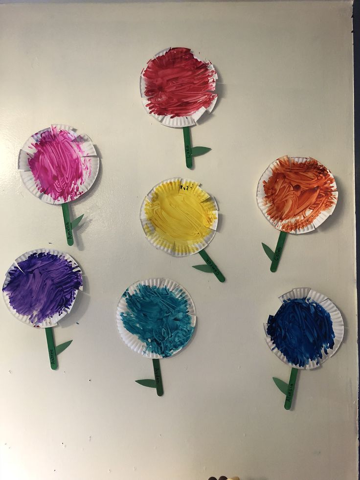 paper plate flowers are arranged on a white board with crayons in the middle