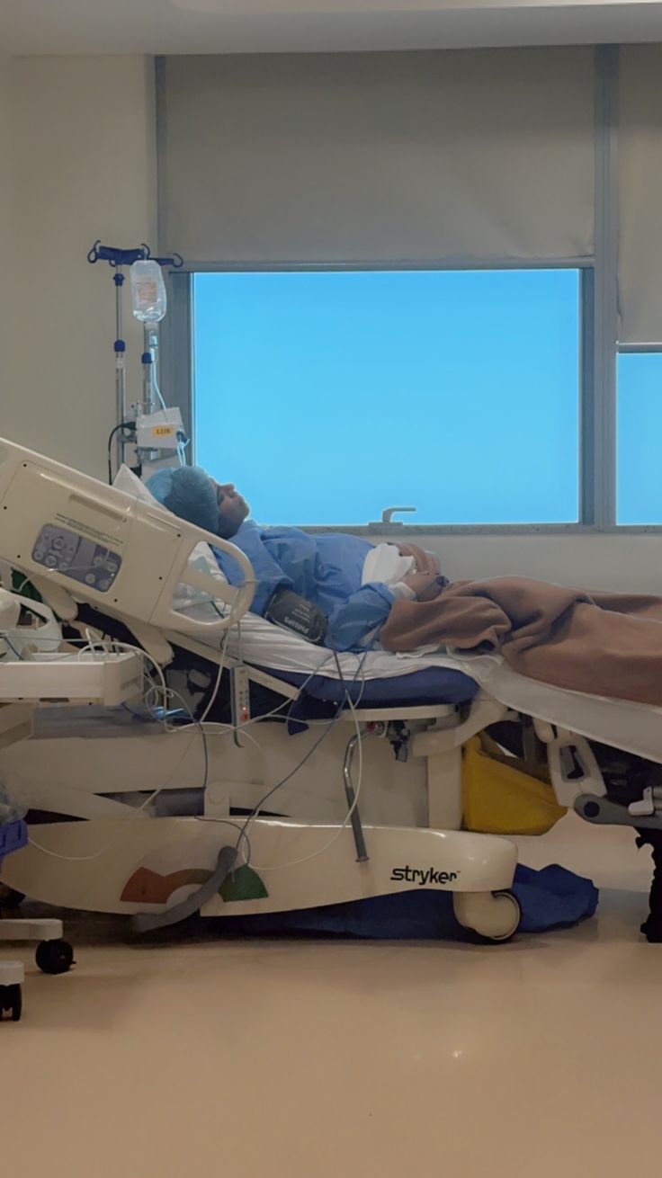 an empty hospital room with medical equipment on the floor and two people sleeping in bed