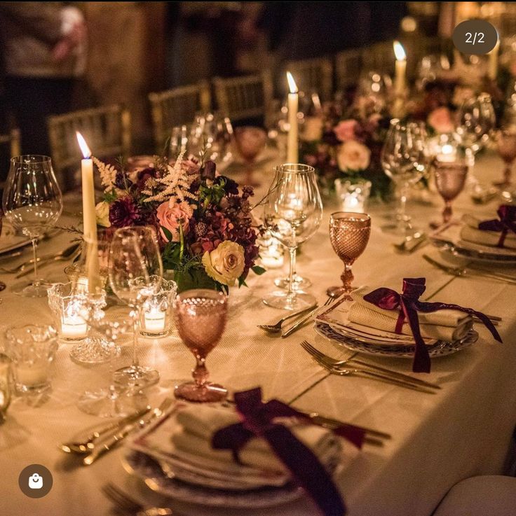 the table is set with candles, plates and silverware for an elegant dinner party