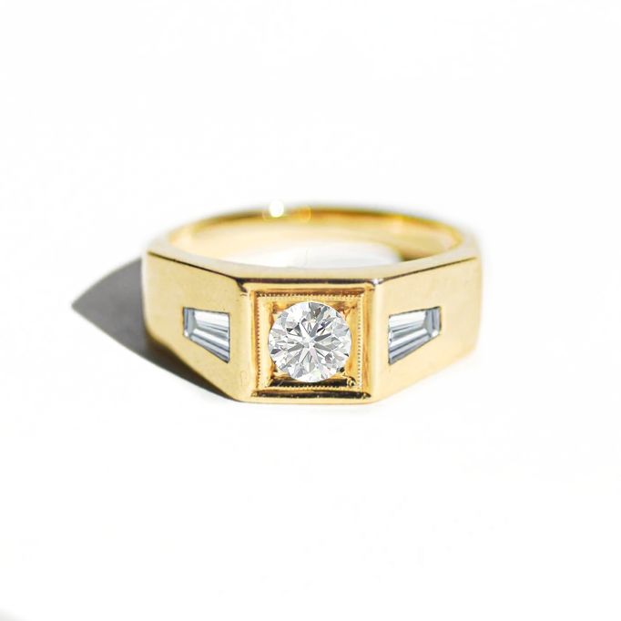 a yellow gold ring with two baguettes and a single diamond in the center