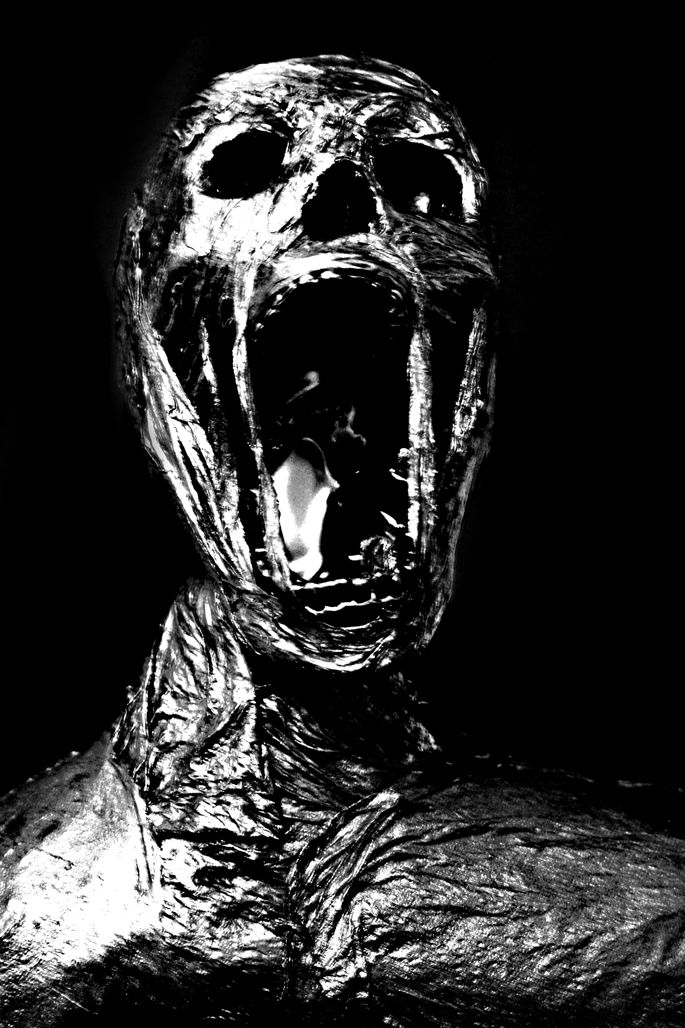 a black and white photo of a creepy creature with its mouth open in the dark