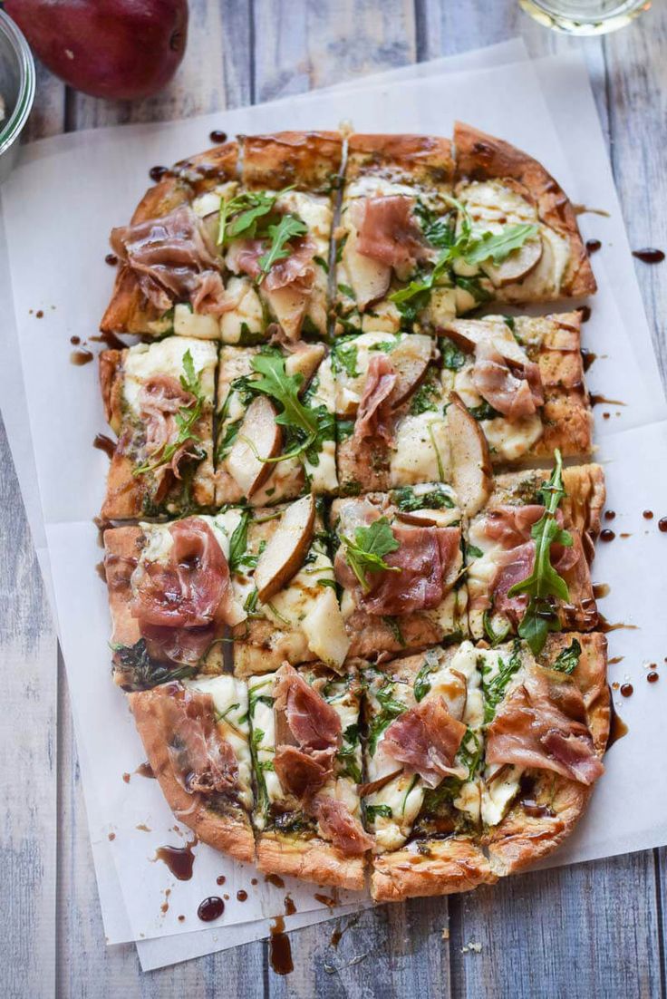 a pizza sitting on top of a cutting board covered in toppings next to a glass of wine