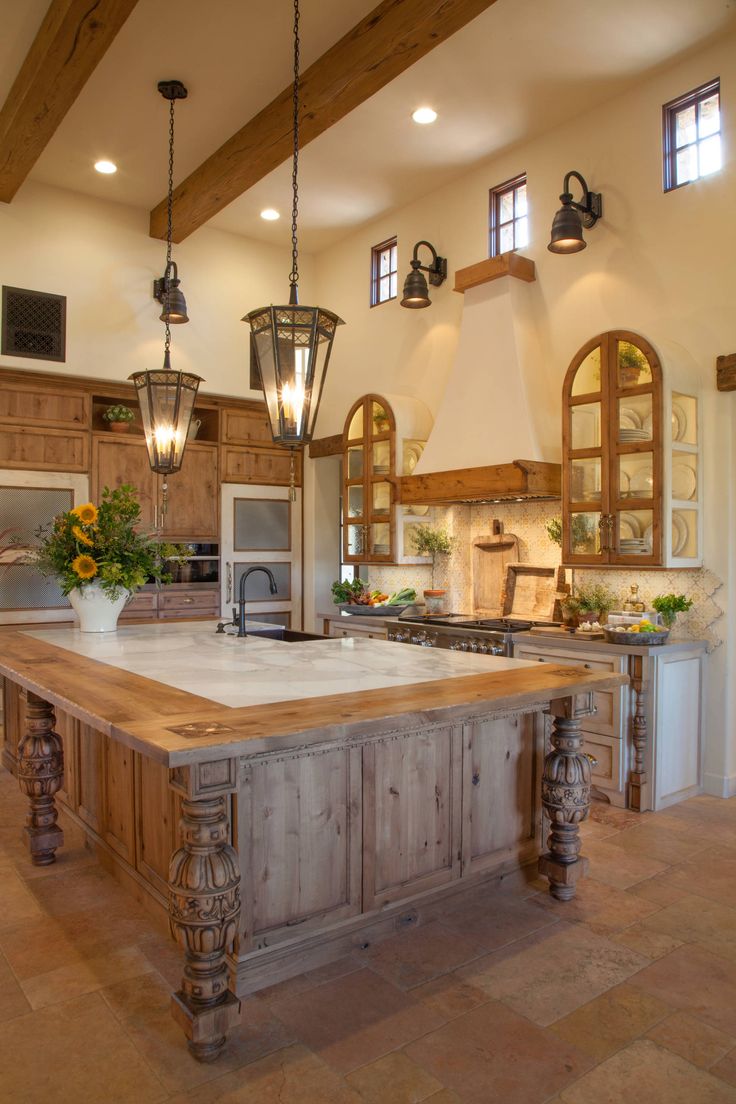 a large kitchen with an island in the middle and lights hanging from it's ceiling