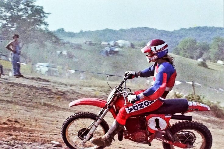 a man riding on the back of a red dirt bike