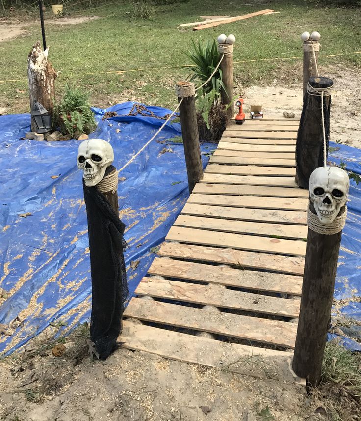 there are two fake skulls on the wooden bridge that is being built into the ground