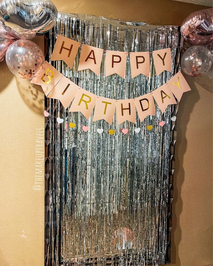 a happy birthday banner hanging from the side of a wall next to balloons and streamers