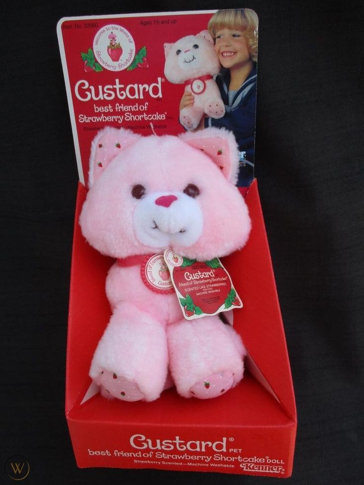 a pink teddy bear sitting in a red box with its tag on it's chest