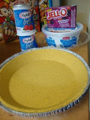 a pie pan sitting on top of a wooden table next to containers of yogurt